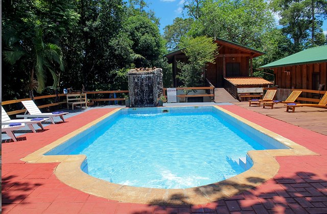 Piscina del lodge con la cascada de piedra y el jardín